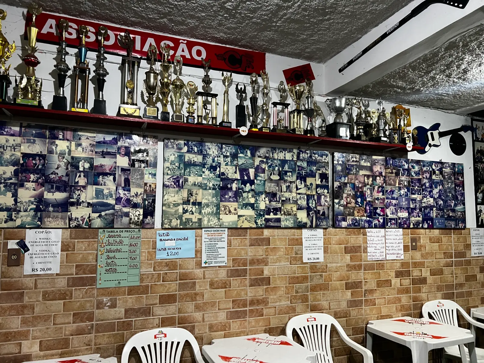 Parede do Bar do Dito Cavichi com troféus da Associação CF e mural de fotos antigas de frequentadores, Brazópolis MG